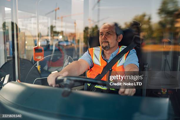 bus driver wearing safety vest and seatbelt driving carefully - responsabilidade imagens e fotografias de stock
