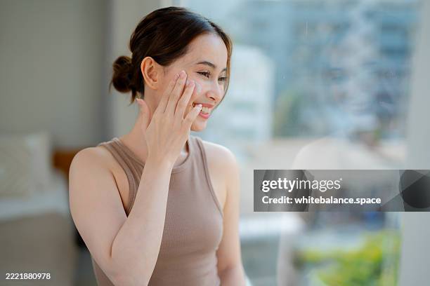 close-up shot of young woman applying a multipurpose lotion to her neck and face - close up of womans neck and clavicles stock pictures, royalty-free photos & images