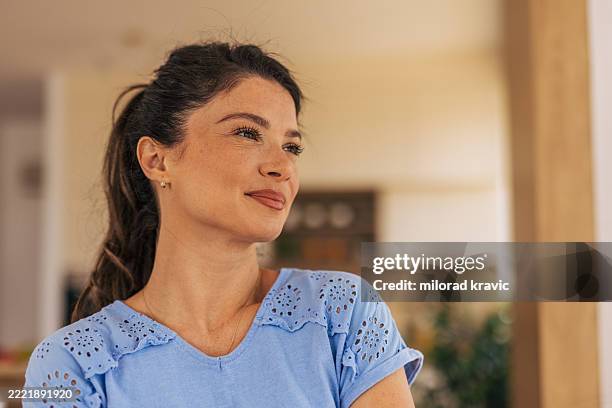 serene woman smiling and looking away at home: contemplation and positivity - selective focus stock pictures, royalty-free photos & images