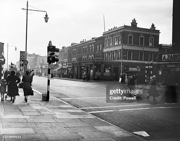 Pedestrians pass a set of traffic lights on Walworth Road in southeast London, England, 23rd January 1956.