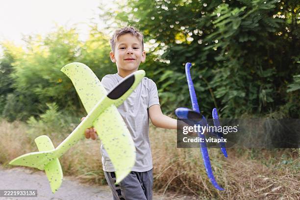 junge mit bunten spielzeugflugzeugen im freien an einem sonnigen tag - jung geblieben stock-fotos und bilder
