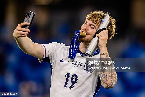 England's forward Harvey Elliott poses for a selfie with the trophy he was awarded for being the best player of the tournament after his team won the...