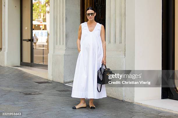 Zina Charkoplia wears white wide Dissh dress, Chanel ballerinas, black Hermes bag on June 24, 2025 in Barcelona, Spain.