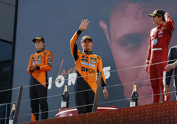 Winner McLaren's British driver Lando Norris celebrates on the podium next to second placed McLaren's Australian driver Oscar Piastri and third...