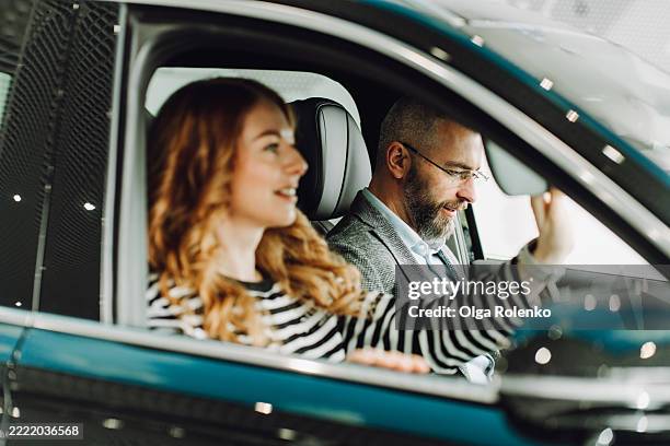 couple sitting in new car, adjusting rearview mirror - fahrgemeinschaft stock-fotos und bilder