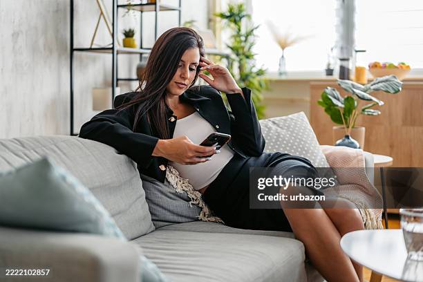 tired young businesswoman using phone while sitting on the sofa at home - angry typing stock pictures, royalty-free photos & images