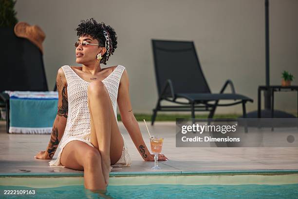 giovane donna che si rilassa a bordo piscina con un cocktail durante le vacanze estive - bordo piscina foto e immagini stock