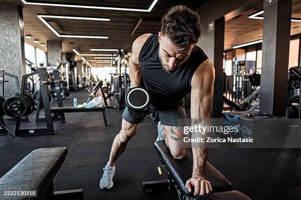 hombre en forma haciendo ejercicio con mancuernas en el gimnasio - centro de bienestar fotografías e imágenes de stock