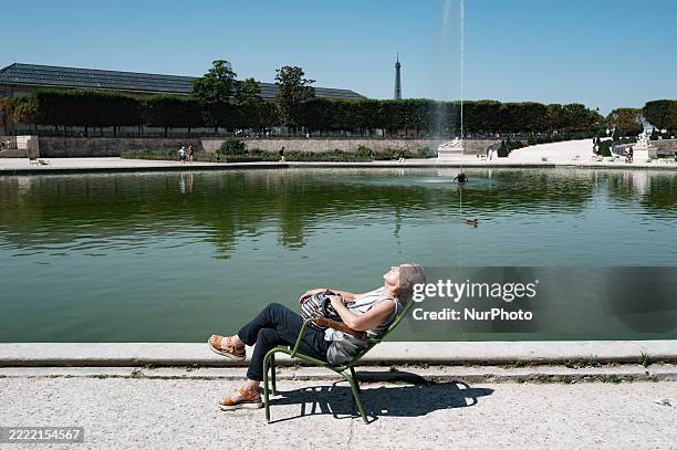 In Paris, France, on June 21 a woman sits on a chair in Tuileries Garden Park as 84 departements are placed on 'vigilance orange canicule' , with...