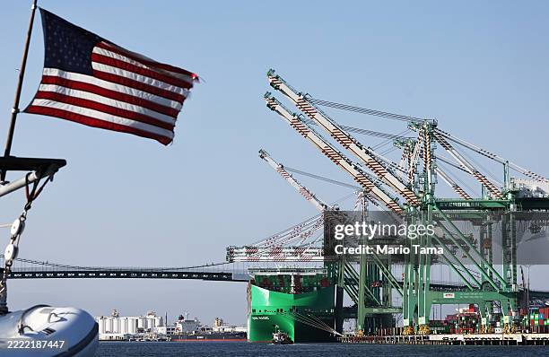 An American flag flies in front of shipping containers stacked on a container ship at the Port of Los Angeles on June 25, 2025 in Los Angeles,...