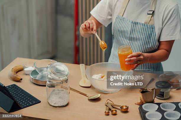 pastry chef pouring honey into mixing bowl for baking banana bread - maatlepel stockfoto's en -beelden