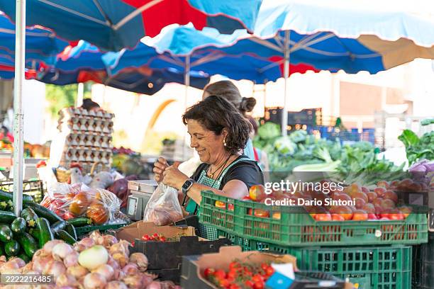 gemüsehändler wiegt frische produkte auf dem bauernmarkt - marktstand stock-fotos und bilder