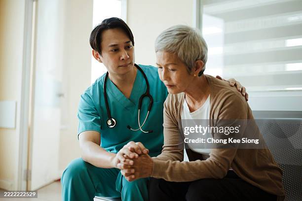 caring physician supporting senior in medical hallway - patient bad news stock pictures, royalty-free photos & images