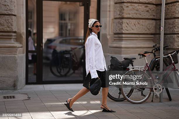 Anna Winter is seen wearing a white oversized tailored shirt with long sleeves, buttoned with only two buttons at chest height from COS; a black...