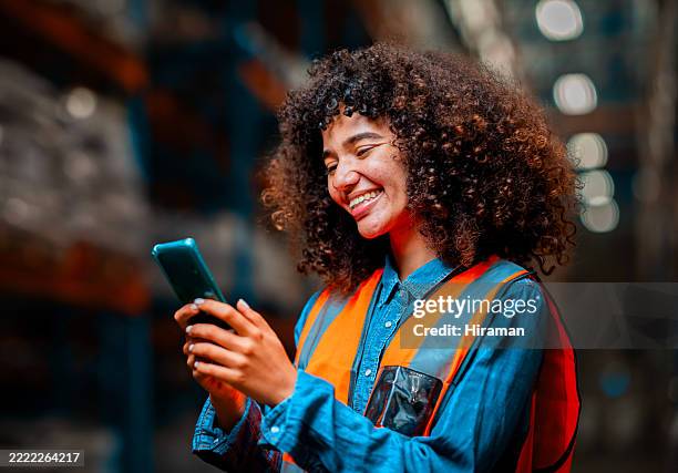 warehouse worker smiling while using smartphone in logistics facility - warehouse worker stock pictures, royalty-free photos & images