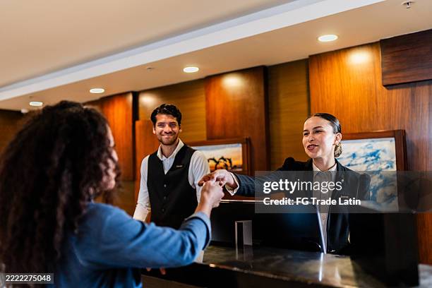 young receptionist woman giving key card to guest at hotel - reception bildbanksfoton och bilder