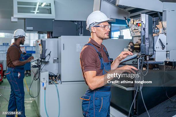 factory worker is programming a cnc milling machine with a tablet computer. - manual worker milling machine operator photos et images de collection