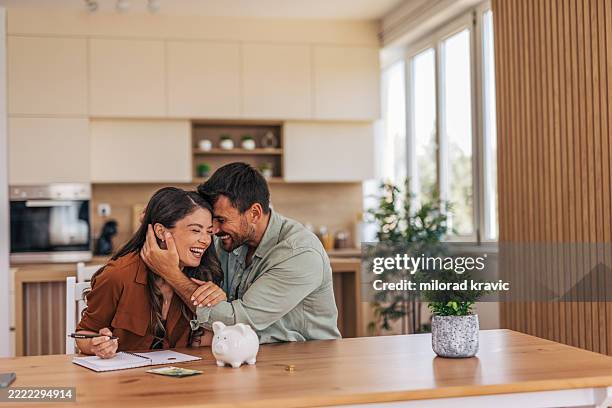 happy couple budgeting and saving money at home - todas as unidades monetárias europeias imagens e fotografias de stock