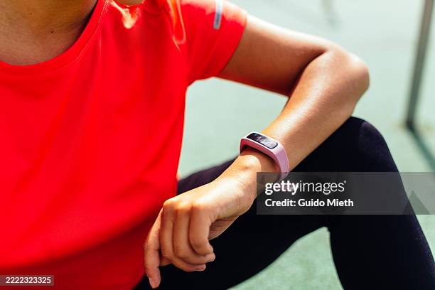 beautiful young woman doing sport outdoor in urban scene while looking at her smartwatch. - wearable stock-fotos und bilder