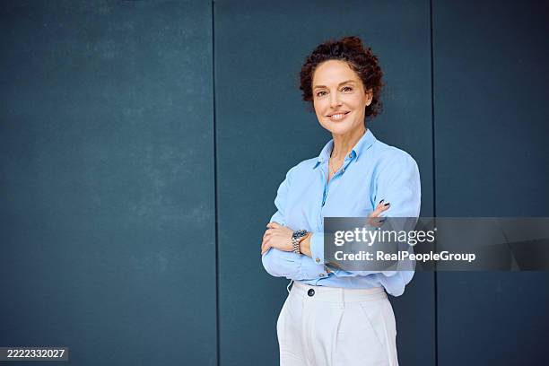confident businesswoman smiling with arms crossed, looking at camera - blue shirt stock pictures, royalty-free photos & images