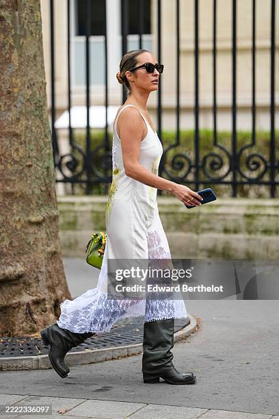 Guest wears black rectangular sunglasses and a sleek hairstyle pulled back into a bun. The dress is sleeveless with a white bodice featuring subtle...
