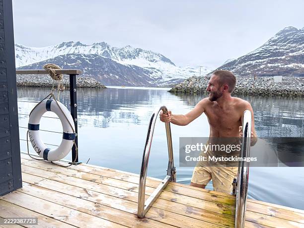 man climbing ladder from calm fjord water - buoy stock pictures, royalty-free photos & images