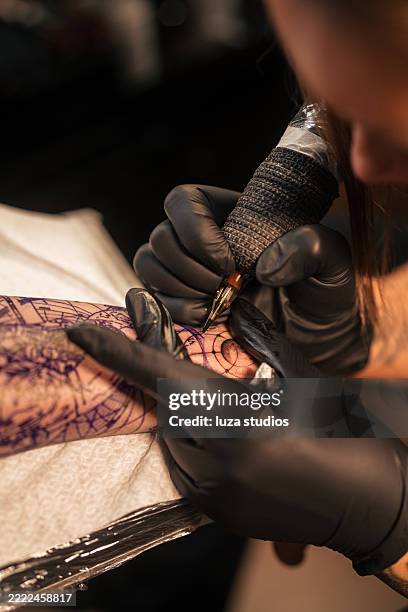 close-up of a tattoo artist working on a detailed arm piece - hand stencil stock pictures, royalty-free photos & images