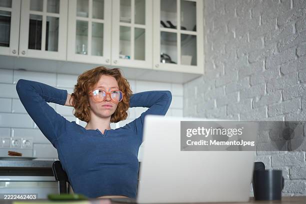 tired overworked woman freelancer sitting at kitchen table with laptop. remote work mental health challenges. upset student girl wearing eyeglasses feeling unmotivated to study online - staring at screen stock pictures, royalty-free photos & images