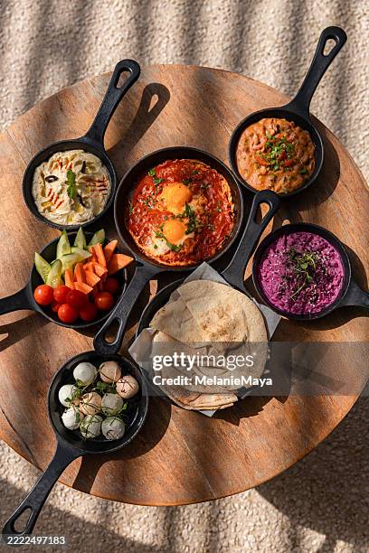 middle eastern arabic breakfast food mezze bowls with hummus, shakshouka, salads and lebaneh cheese served in lebanese restaurant - food styling stock pictures, royalty-free photos & images