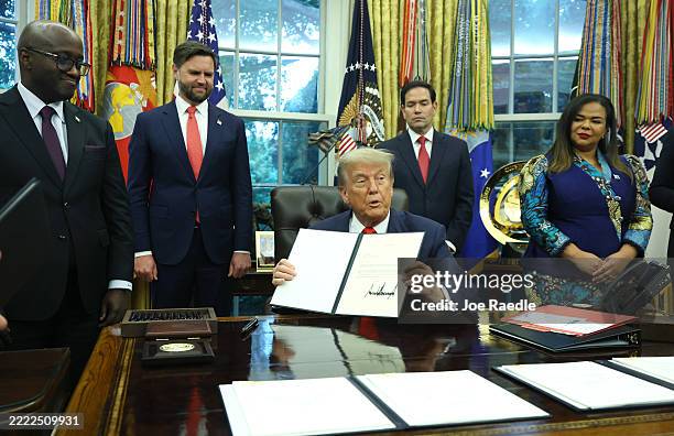 President Donald Trump sigs a letter of congratulations as he meets with Minister of Foreign Affairs and Cooperation of Rwanda Olivier Nduhungirehe...