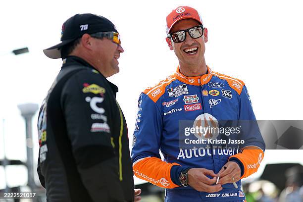 Joey Logano, driver of the Autotrader Ford, and BJ McLeod, driver of the Pigeon Forge Racing Coaster Chevrolet, talk on the grid during qualifying...