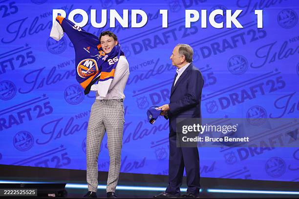 Matthew Schaefer puts on an Islanders sweater as NHL commissioner Gary Bettman looks on after being drafted by the NY Islanders with the number one...