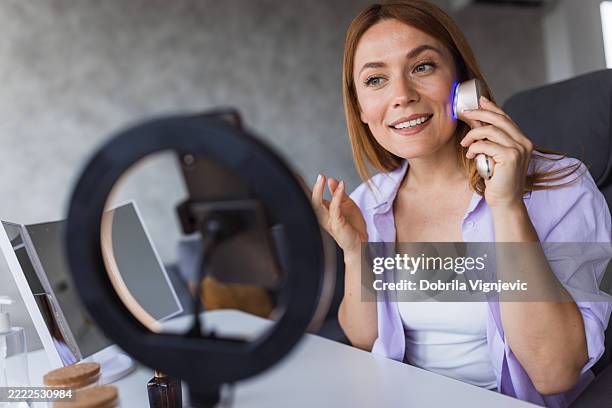 influencer mit led-lichttherapiegerät bei der videoaufnahme - gesichtsmassage stock-fotos und bilder