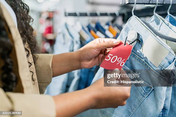 woman shopping for clothes on sale and holding the discount tag - outlet store stock pictures, royalty-free photos & images
