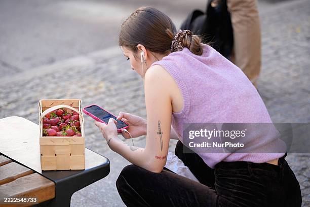 Woman with a basket of strawberries is seen at a bus stop in Warsaw, Poland on 01 July, 2025.