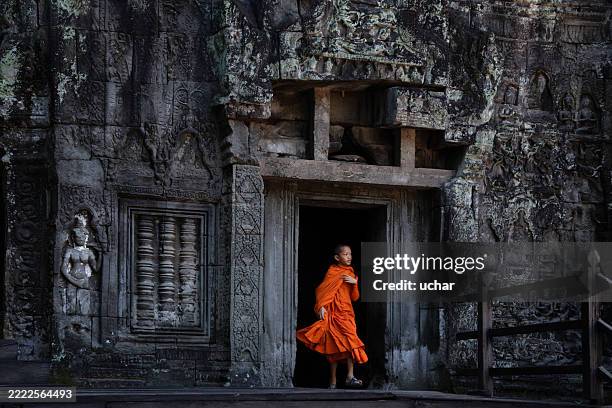 junger buddhistischer mönch, der aus einem tempel in angkor wat, siem reap, kambodscha geht - angkor wat stock-fotos und bilder