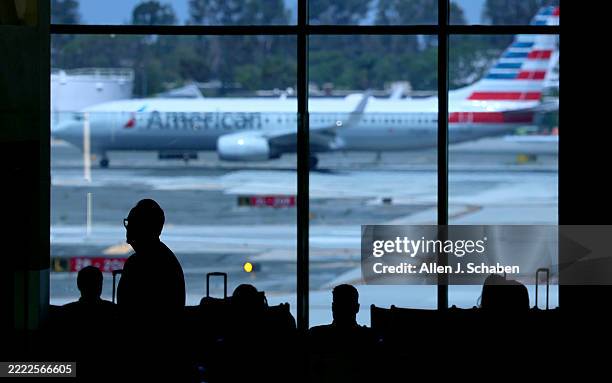 Santa Ana, CA Travelers are silhouetted as they wait to board their planes during a getaway for the Fourth of July holiday at John Wayne Airport in...