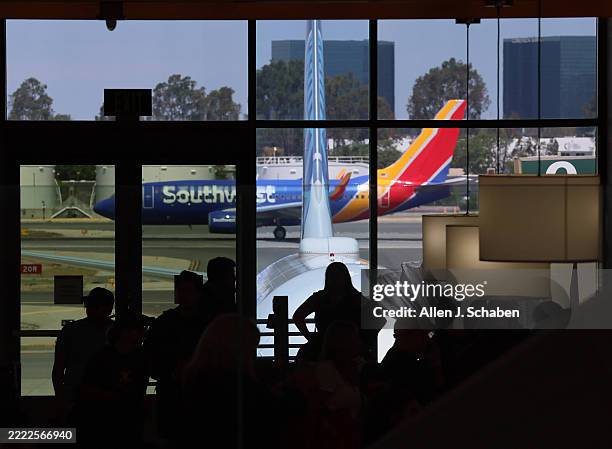 Santa Ana, CA Travelers are silhouetted as they wait to board their planes during a getaway for the Fourth of July holiday at John Wayne Airport in...