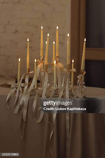 burning candles with ribbons on festive table in warm restaurant interior with red wall - candle light stock pictures, royalty-free photos & images
