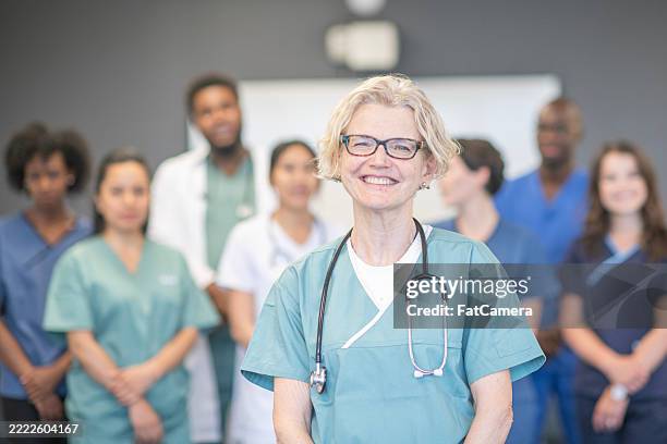 selbstbewusster leitender arzt, der ein vielfältiges medizinisches team in einer gesundheitseinrichtung leitet - fairness stock-fotos und bilder