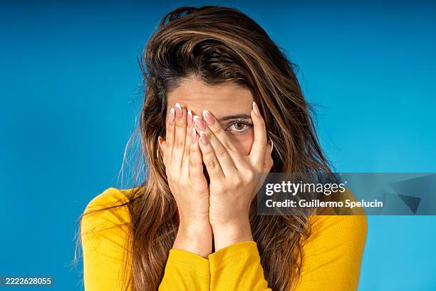 young woman hiding face expressing fear and shame - verlegen stockfoto's en -beelden