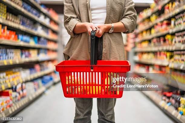 woman holding shopping basket in supermarket groceries corridor - varukorg bildbanksfoton och bilder