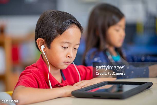 elementary school students using tablets for educational activities in classroom - elementary age stock pictures, royalty-free photos & images