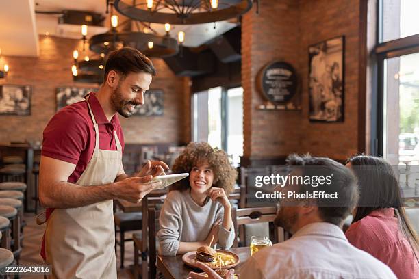 friendly waiter using tablet to take guest order - empregado de mesa imagens e fotografias de stock