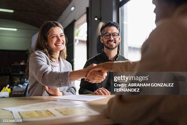 business partners shaking hands in an office after finalizing a contract, celebrating a successful agreement and fostering collaboration - recruitment stock pictures, royalty-free photos & images