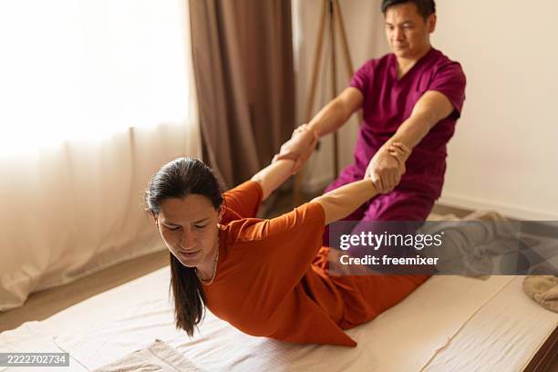 thai male chiropractor or physical therapist working with caucasian female patient - distorted stock pictures, royalty-free photos & images