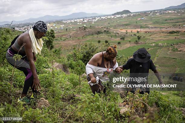 Hiker helps another one descending a hill during a group hike on the outskirts of Abuja, Nigeria, on June 28, 2025. With no trail post in sight, the...