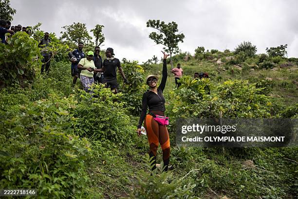 Hiker poses for a photograph as she descends a hill during a group hike on the outskirts of Abuja, Nigeria, on June 28, 2025. With no trail post in...
