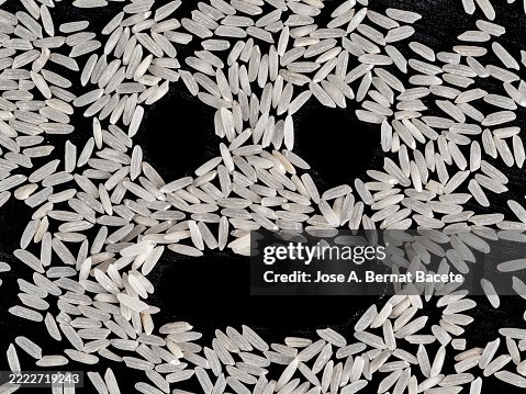 Grains of raw rice with a face drawn on them on a black background. Grains of raw rice with a face drawn on them on a black background.