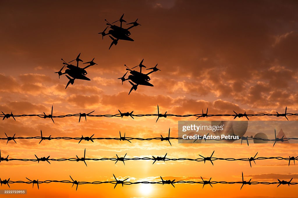 Kamikaze drones over barbed wire at sunset